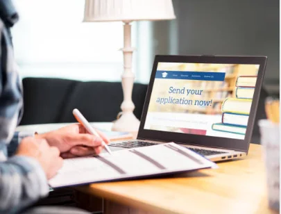 student writing personal statement scholarship application laptop university desk 2026